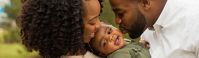 parents holding and kissing happy child